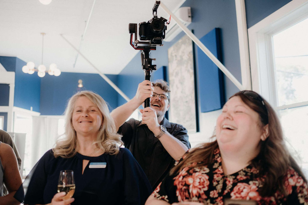 Gardiner Bryant has camera on gimbal rig with smiling faces in the foreground